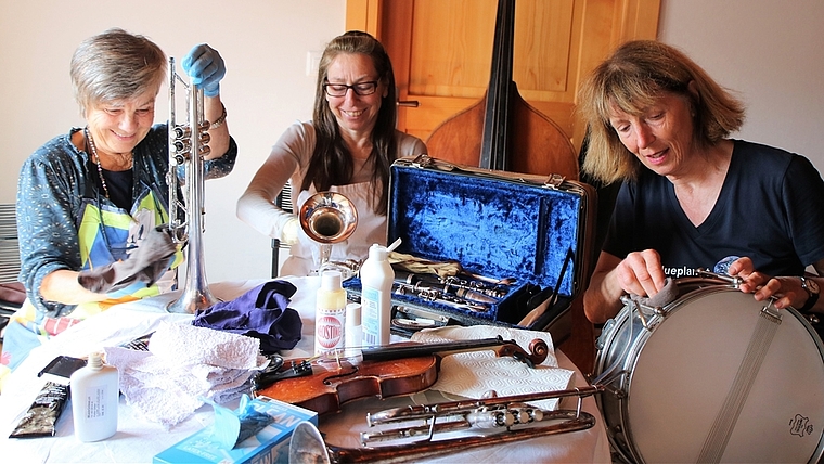Susanne Lendenmann, Marina Gantert und Cornelia Diethelm (von links) putzen und kontrollieren die Musikinstrumente vor dem Versand nach Kolumbien. Wer wohl auf der kleinen 1/4-Violine spielen wird?<em> (Bild Regula Zellweger)</em>