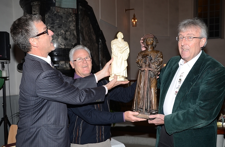 Schriftsteller Ueli Leutwyler (rechts) überreicht Skulpturen der Reformatoren Zwingli und Luther als Geschenke: Pfarrer Thomas Maurer und Kirchenpfleger Bruno Grob (Mitte) sind höchst erfreut. (Bild Martin Mullis)