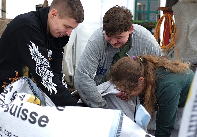 Drei junge Erwachsene mit einem geschützten Ausbildungsplatz im Götschihof der Solvita-Stiftung arbeiten beim Abmischen der Gartenerde zusammen. (Bild Salomon Schneider)