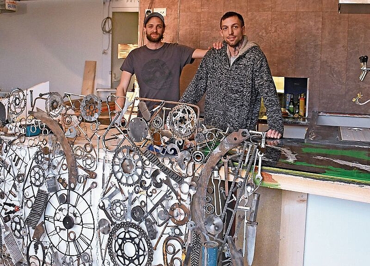 Noch wird fleissig gebaut: Nino Pianezzi (rechts) und Matthias Huber hinter dem künftigen Bartresen, der mit der Verkleidung aus zusammengelöteten Metallelemeneten – eine Eigenkreation – in Szene gesetzt wird. (Bild Livia Häberling)
