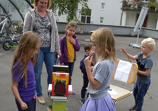 Die Kinder vergnügen sich am Jubiläumsfest beim Bücherstapeln.