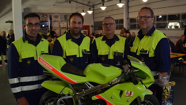 Ein persönliches Feuerwehr-Pocket-Bike für Markus Tschan (2.v.r.). Seine Nachfolge als Kommandant tritt Martin Pfister (2.v.l.) an, Daniel Künzi (links) wird Ausbildungschef, Stefan Kämpfer (rechts) bleibt Vizekommandant. (Bild Thomas Stöckli)
