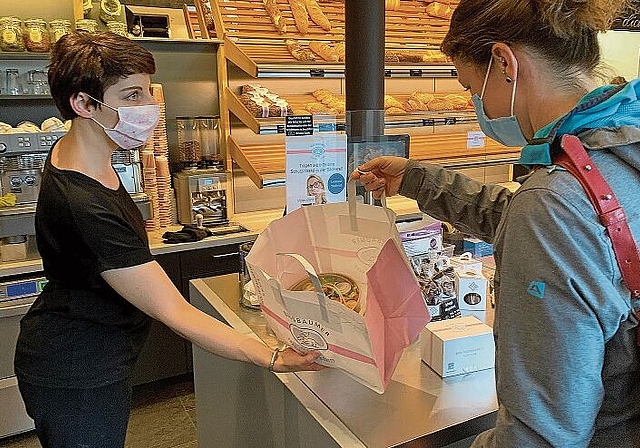 Eine Kundin holt sich in der Bäckerei Nussbaumer in Affoltern ein über die App bestelltes Päckli mit Lebensmitteln ab. (Bild Stefan Schneiter)
