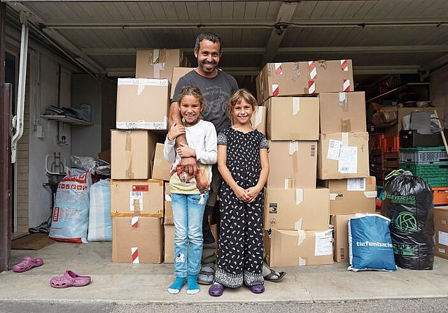 Vor den Kartonschachteln voller Spendenkleidern: Said Ousaadane mit seinen Töchtern Dunya und Nasira. (Bild Luc Müller)