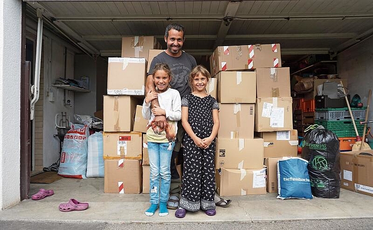 Vor den Kartonschachteln voller Spendenkleidern: Said Ousaadane mit seinen Töchtern Dunya und Nasira. (Bild Luc Müller)