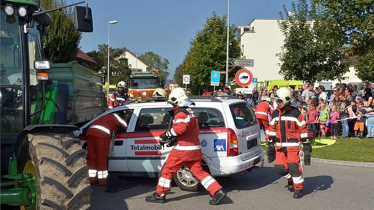 In Unfall involvierter Personenwagen und Traktor: Feuerwehr-Einsatz unter genauer Beobachtung einer grossen Zuschauermenge. (Bild Martin Mullis)