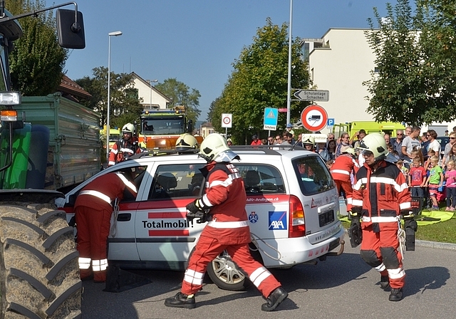 In Unfall involvierter Personenwagen und Traktor: Feuerwehr-Einsatz unter genauer Beobachtung einer grossen Zuschauermenge. (Bild Martin Mullis)