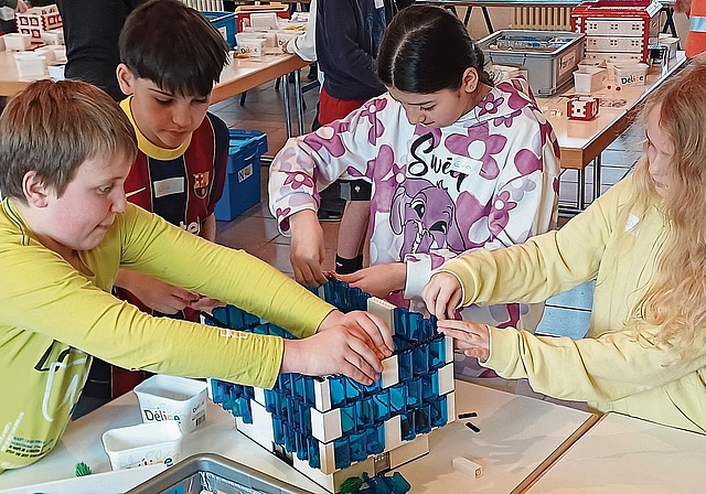 Konzentriert setzen die Kinder nach einem Plan gemeinsam ein Bauwerk aus Legosteinen zusammen. (Bild Regula Zellweger)