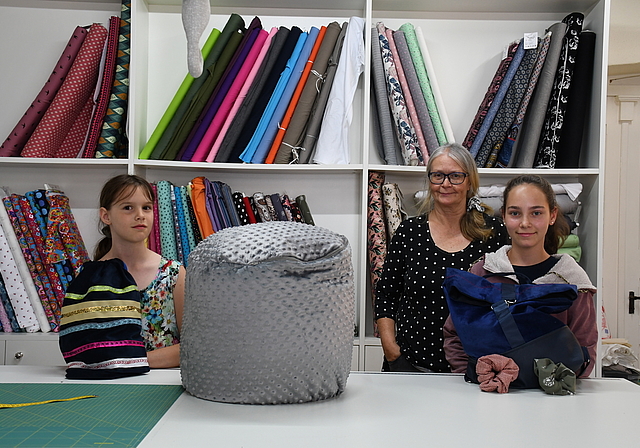 Emilia (links) hat mithilfe von Kursleiterin Hanni Stutz einen Turnsack und ein Blumenkleid genäht, Crisitna einen Rucksack und Haargummis. (Bild lhä) 