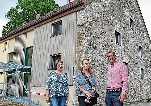Die alte Feldsteinmauer ist prägendes Element des Neubaus für die Aussenwohngruppe der «Puureheimet Brotchorb». Von links: Irene Simoni, Leitung Betreuung, Stiftungsratspräsidentin Beatrice Gfeller und Moritz Arbenz, Leitung Betrieb. (Bild Thoma