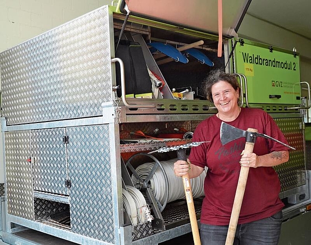 Luana Maggetti, Feuerwehr-Offizierin und Leiterin der Waldbrand-Gruppe in Affoltern, mit dem Waldbrand-Anhänger und den wichtigsten Werkzeugen: Gorgui (links) und Wiedehopf-Hacke. (Bild Thomas Stöckli)