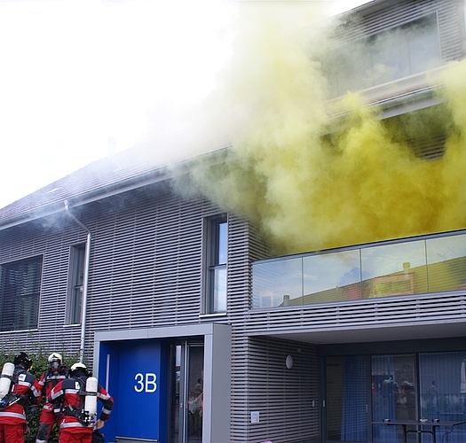 Dichter Rauch kommt aus dem Meilihof-Wohnhaus B in Ebertswil. (Bilder tst.). Ein Bewohner wird aus dem Badezimmer gerettet – eine Betreuerin ist dabei. Am Tag der offenen Tür dürfen anschliessend auch die Kleinen «löschen». Die Bewohner werden evakuiert...