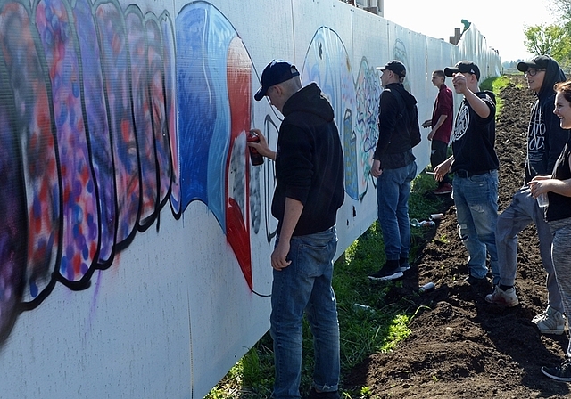 Gemeinsame Arbeit der Hausemer Jugendlichen am Graffiti auf der Abschrankung der Baustelle Törlenmatt. (Bild Bernhard Schneider)