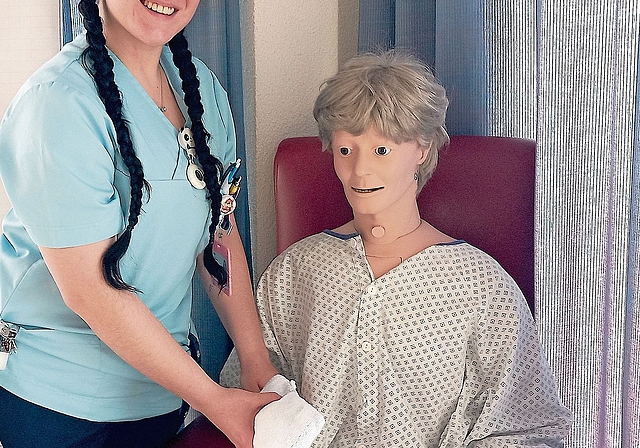 Ladina Simshäuser demonstriert an einer Übungspuppe, wie man als Fachperson Gesundheit Patienten bei der Körperpflege unterstützt.
