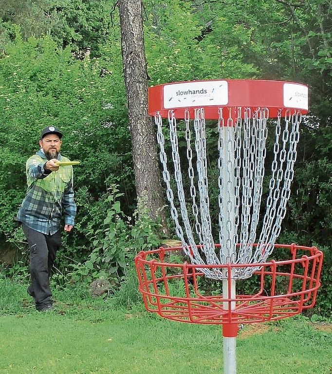 Benji Fischer beim Abwurf. Die Ketten halten den Flug der Disc-Golf-Scheibe auf und diese fällt in den darunter liegenden Korb, das Ziel. (Bild Nepita Santiago)