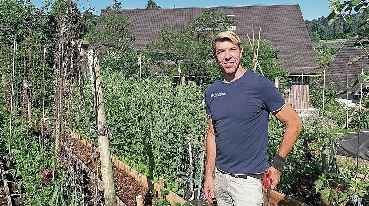 Hanspeter Leder ist bereit für Garten-Taten. Im Hintergrund weisen Fähnchen zum erntebereiten Gemüse. (Bild Sandra Claus)