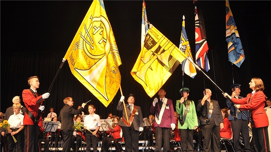 Fahnenträger Silvan Rigoni mit dem neuen Jumba-Banner (links), das von Vertretern der Ämtler Musikvereine begrüsst wird. (Bilder Werner Schneiter)
