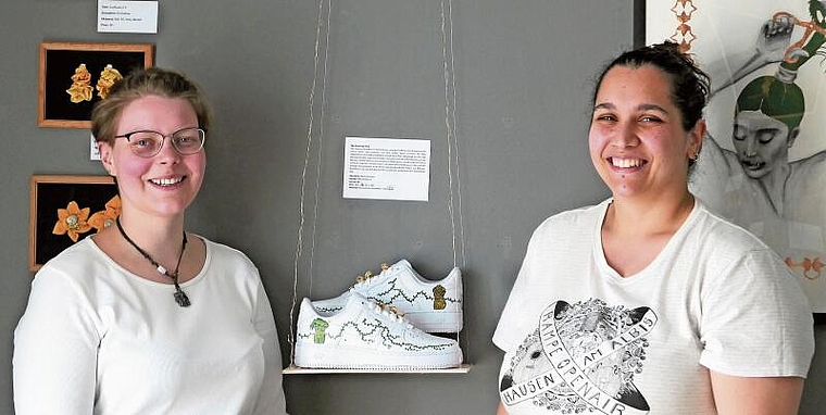 Souraya Hamad (rechts) und Os Rudow vor ihren Werken in der KommBox. Nicht im Bild: Mona Hachem, welche die Schuhe mit Acrylfarben bemalt hat. (Bild Regula Zellweger)