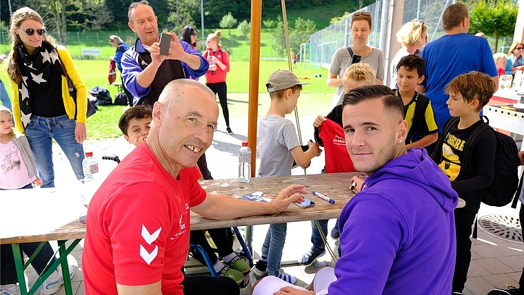 Shani Tarashaj, rechts, beim Autogramme-Schreiben am Tisch des FC Hausen. Links Nachwuchstrainer Heinz Rütti.<em> (Bild Martin Platter)</em>