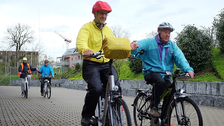 Teilnehmende an der E-Bike Schulung geben sich die Hand, um gleichmässiges, einhändiges Fahren zu üben. (Bild sals)