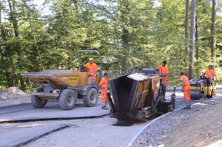 Zum Glück im Schatten des Waldes: Belagseinbau mit heissem Asphalt verstärkt die Hitze. (Bild Martin Mullis)