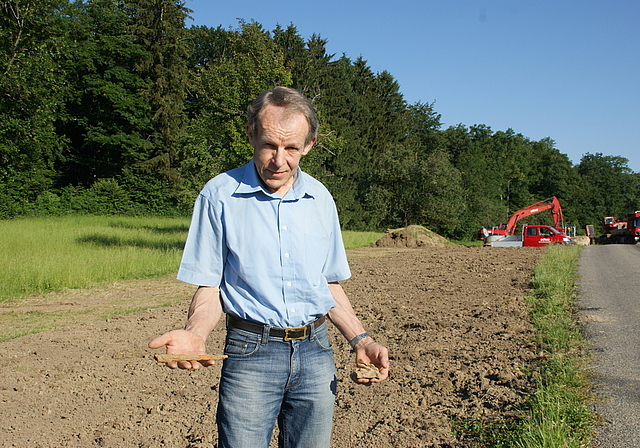 Grabungstechniker Johannes Weiss zeigt den eisernen Tüllenmeissel (links) und das Keramikstück mit dem Abdruck von Rutengeflecht, die er im mittlerweile zugeschütteten Graben in Hänikon, Aeugst, entdeckt hat. (Bild Thomas Stöckli)