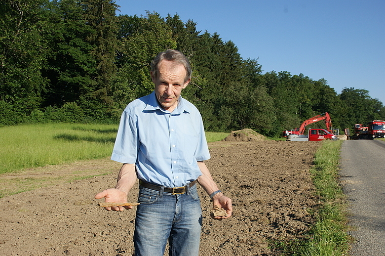 Grabungstechniker Johannes Weiss zeigt den eisernen Tüllenmeissel (links) und das Keramikstück mit dem Abdruck von Rutengeflecht, die er im mittlerweile zugeschütteten Graben in Hänikon, Aeugst, entdeckt hat. (Bild Thomas Stöckli)