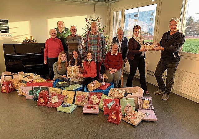 Niki Greco (rechts) übergibt Seewadel-Geschäftsführerin Verena Feller symbolisch eines der 63 Geschenke, denen allen eine Weihnachtsgeschichte beigelegt ist. Ihnen zur Seite einige der glücklichen Seniorinnen und Senioren des Seewadel sowie drei 