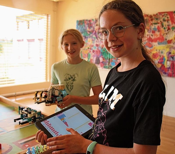 Anja Wunderli und Timea Gyenge zeigen, wie das Legoroboter-Fahrzeug auf dem iPad programmiert wird.