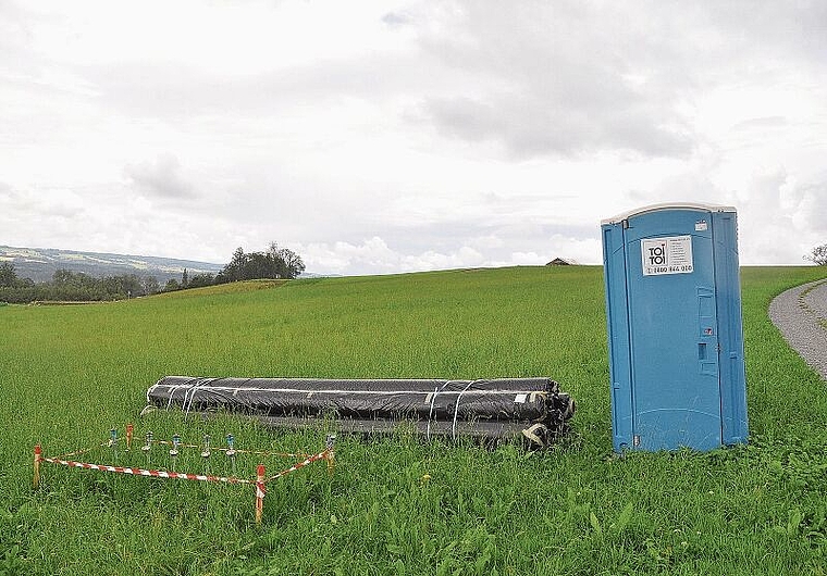 Toilette, Rohre und Messgeräte stehen bereit: Aufgrund der Witterung ist noch nicht klar, wann das Areal im Vordergrund mit hochwertigem Erdreich vom Bau der Limmattalbahn aufgewertet werden kann. (Bild Werner Schneiter)