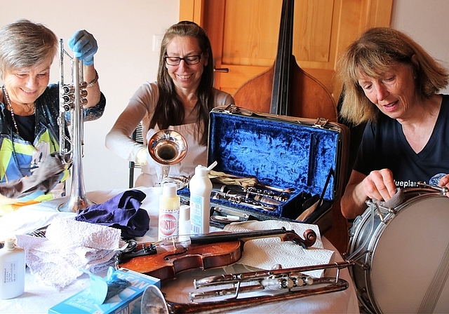 Susanne Lendenmann, Marina Gantert und Cornelia Diethelm (von links) putzen und kontrollieren die Musikinstrumente vor dem Versand nach Kolumbien. Wer wohl auf der kleinen 1/4-Violine spielen wird?<em> (Bild Regula Zellweger)</em>