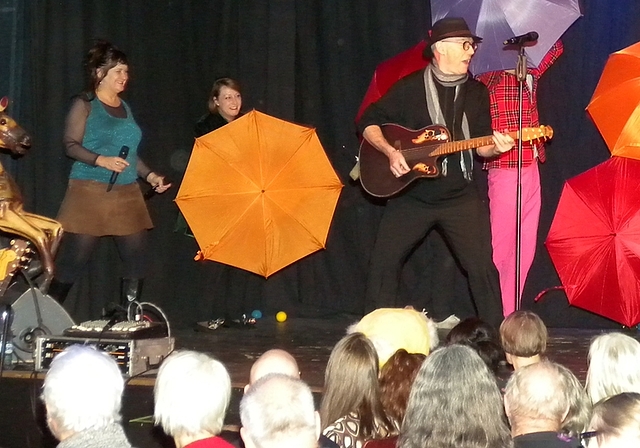 Überraschende, farbige Effekte auf der Bühne. Von links: Gigi Moto, Beat Hebeisen mit der Gitarre, Bruno Amstad und Shirley Grimes. Im Hintergrund das Sextett Sixtones mit den Schirmen.