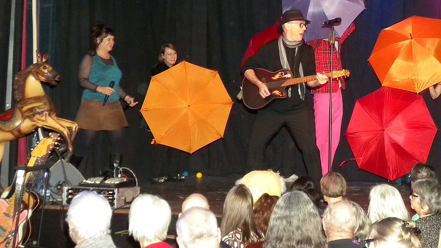 Überraschende, farbige Effekte auf der Bühne. Von links: Gigi Moto, Beat Hebeisen mit der Gitarre, Bruno Amstad und Shirley Grimes. Im Hintergrund das Sextett Sixtones mit den Schirmen.

