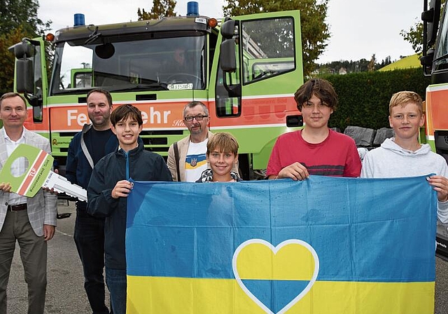 Die Ukraine-Botschaftsvertreter, Kommandant Martin Pfister (2. v.l.) und ukrainische Schulkinder mit Nationalfahne vor dem Tanklöschfahrzeug.