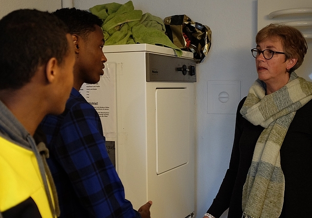 Maria Kapossy erklärt den jungen Männern, wie viel Waschmittel verwendet werden sollte, damit das Einfüllfach der Waschmaschine nicht verklebt. (Bild Salomon Schneider)