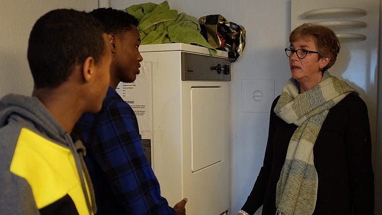 Maria Kapossy erklärt den jungen Männern, wie viel Waschmittel verwendet werden sollte, damit das Einfüllfach der Waschmaschine nicht verklebt. (Bild Salomon Schneider)
