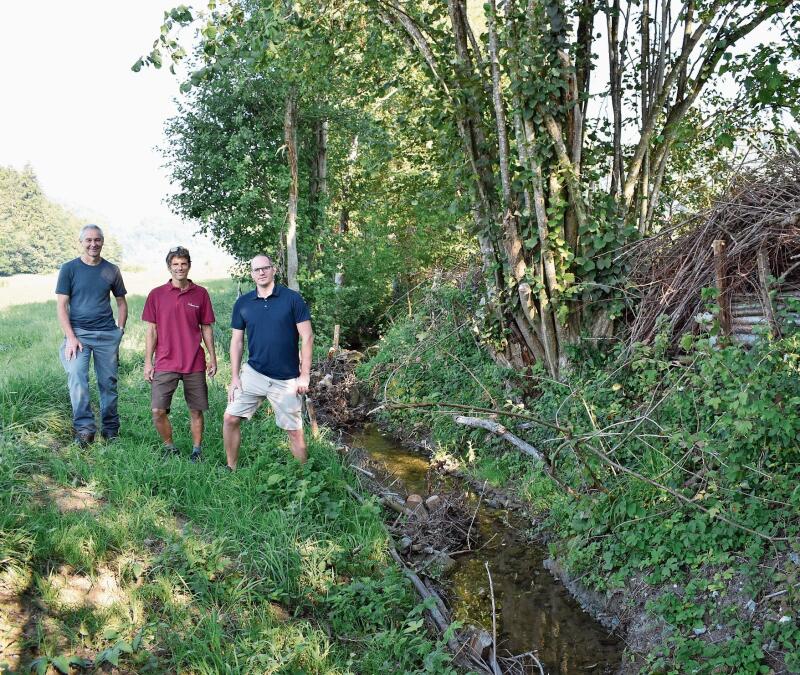 Sie freuen sich über das gelungene Projekt, hier mit Asthaufen am Ufer und Bachverengungen mittels Holz und Steinen. 
Von links: Umweltvorstand Ruedi Taverna, Andreas Nagel von «Rundum Natur» und Tiefbauvorstand Sven Kammer. (Bilder Marianne Voss)