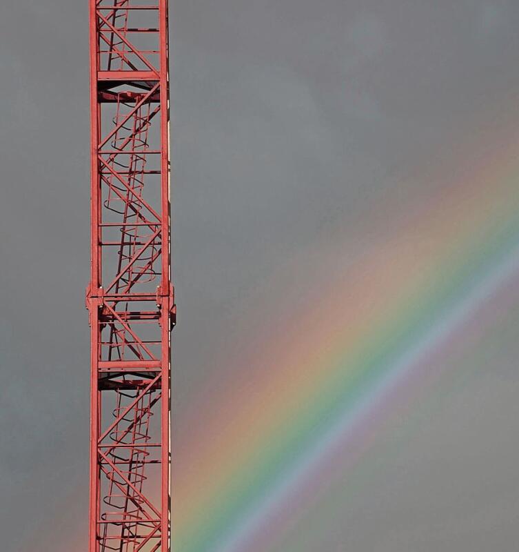 Der Regenbogen in Verbindung mit dem Ausschnitt eines Krans zeigt den Gegensatz von Naturschönheit und technischer Ästhetik.