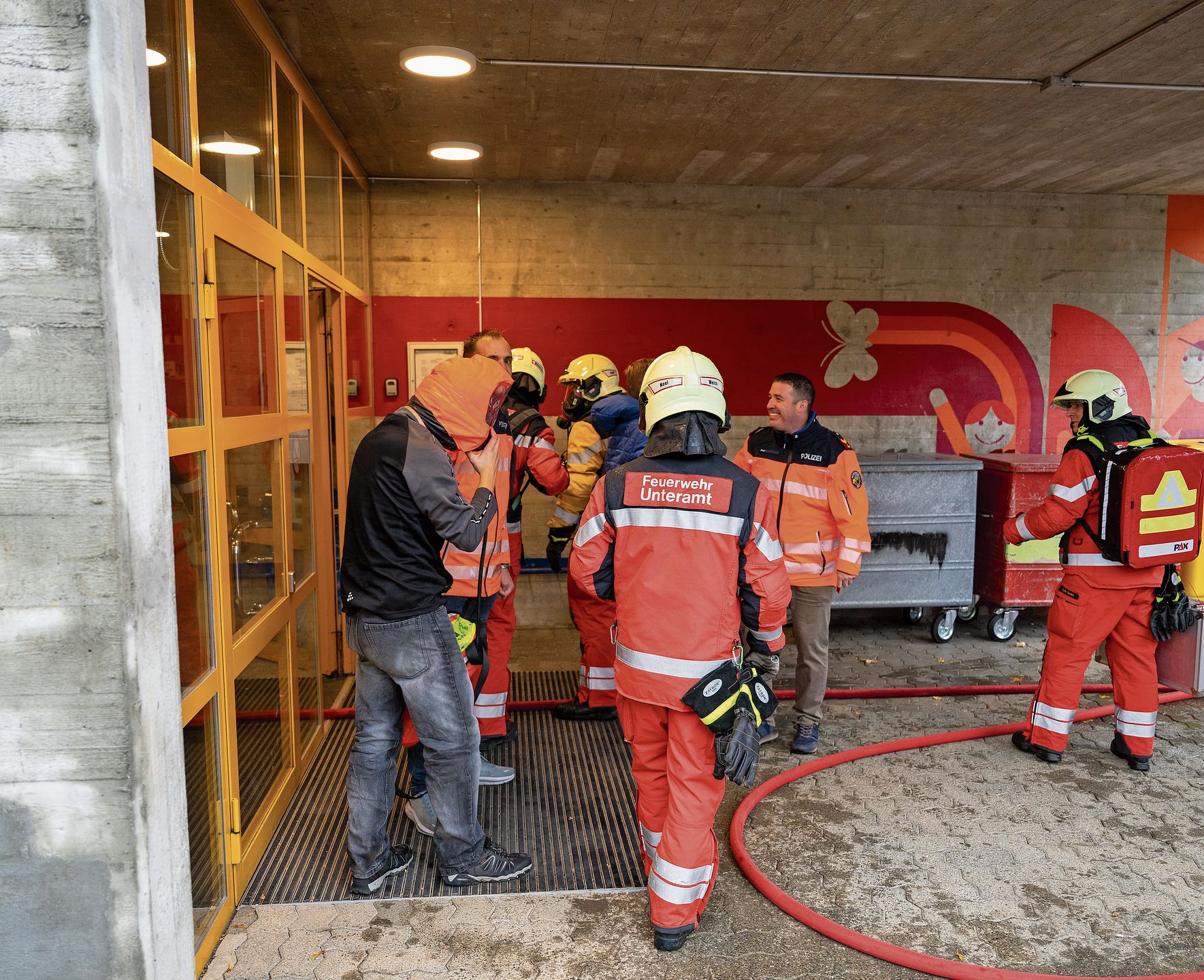 Die Feuerwehr-Sanität wartet vor dem verrauchten Gebäude, um sich den Verletzten zu widmen. Die Feuerwehr-Sanität wartet vor dem verrauchten Gebäude, um sich den Verletzten zu widmen.