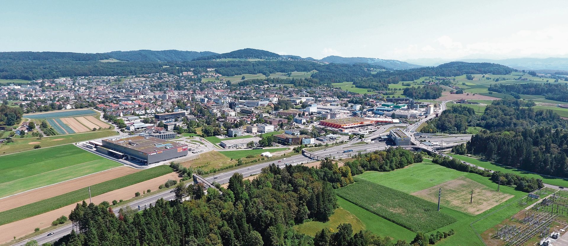 Diese Luftaufnahme aus dem Jahr 2023 zeigt nicht nur die schöne landschaftliche Lage, in die Affoltern eingebettet ist, sondern auch den Wandel der Stadt. Denn den Obi gibt es nicht mehr – dort soll ein Freizeitzentrum entstehen. Zwischen Pfister und Autobahnraststätte hat sich eine Firma aus den Kanton Zug angesiedelt und baut dort kräftig. Auch das Braui-Areal ist noch nicht im Bau. (Archivbild Stefan Felder)