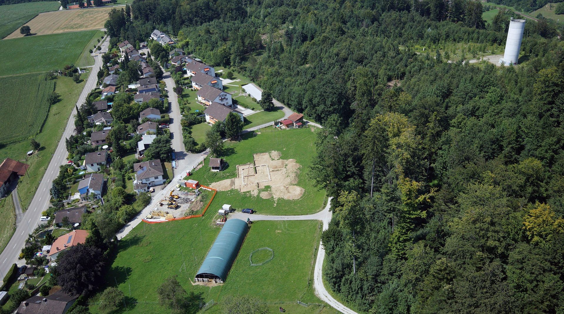 Luftaufnahme der Fundstelle Heidenkirche bei Wettswil. In der Bildmitte das Ausgrabungsgelände auf dem Heidenchilen-Plateau. Im Bereich des Einfamilienhausquartiers liegen bereits im 19. Jahrhundert erwähnte römische Gebäude. (Bild S. Vogt, Kanto Luftaufnahme der Fundstelle Heidenkirche bei Wettswil. In der Bildmitte das Ausgrabungsgelände auf dem Heidenchilen-Plateau. Im Bereich des Einfamilienhausquartiers liegen bereits im 19. Jahrhundert erwähnte römische Gebäude. (Bild S. Vogt, Kantonsarchäologie Zürich)