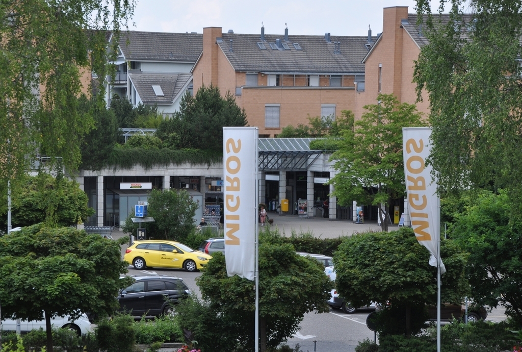 Auf dem Parkplatz des Zentrums Oberdorf wird der Migros-Neubau hochgezogen. (Bild Werner Schneiter)Der Migros-Neubau, vom Jonenbach her gesehen.Auf der grösstenteils überdeckten Piazza sind öffentliche Veranstaltungen möglich. (Visualisierungen zvg.)