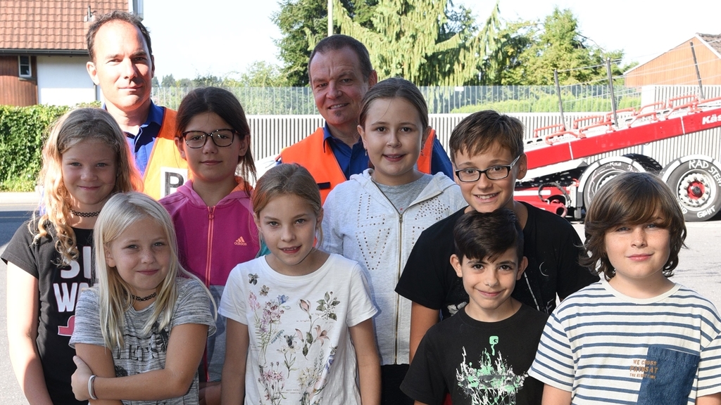 Die Kinder posieren mit den beiden Polizisten Peter Baumann und Patrik Suter für ein Erinnerungsbild.