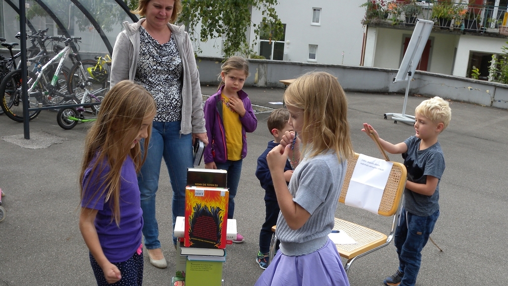 Die Kinder vergnügen sich am Jubiläumsfest beim Bücherstapeln.